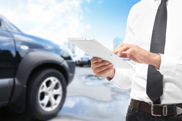 toco warranty good vehicle service contract provider man in white shirt and black tie with form contract in hand black car in the background